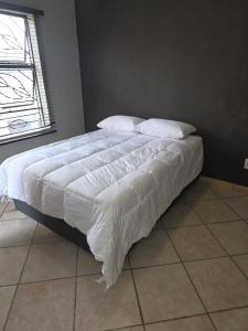 Una cama con sábanas blancas y almohadas en un dormitorio. en The Good Samaritan 2, en Witbank
