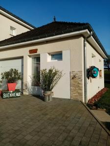a white house with a garage with a potted plant at Le paon de bois avec bain nordique in Saint-Mards-en-Othe