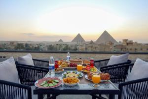 a table with food and drinks on a balcony with pyramids at The Sacred Angle pyramids View in Cairo