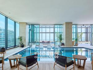 een groot zwembad met stoelen en tafels in een gebouw bij Mitsui Garden Hotel Yokohama Minatomirai Premier in Yokohama