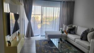 White House At The Blyde Crystal Lagoon في بريتوريا: غرفة معيشة مع أريكة وطاولة زجاجية