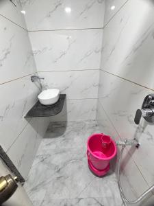 a bathroom with a sink and a pink bucket at Sairam Residency in Ellora