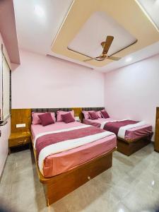 two beds in a bedroom with a ceiling at Sairam Residency in Ellora