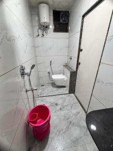 a bathroom with a toilet and a pink bucket at Sairam Residency in Ellora
