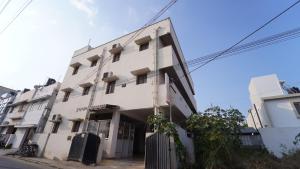 a large white building with windows on a street at Varun Residency New in Coimbatore