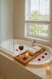 a bath tub with a glass of wine and candles at Novaworld Phan Thiết - Alala Stay in Bình Sum