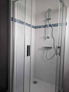 een badkamer met een douche met een glazen deur bij Maison centre de Barfleur in Barfleur