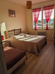 een slaapkamer met 2 bedden en een raam met rode gordijnen bij Maison centre de Barfleur in Barfleur