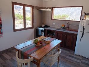 Una cocina con una mesa de madera y un refrigerador. en Cabañas La Nochera, en Tilcara