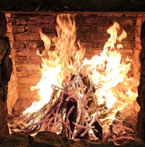 a fire burns inside of a brick fireplace at Pousada Chale da Montanha in Petrópolis