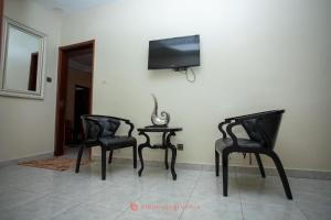 two chairs and a table with a tv on a wall at Residence Cabral in Guediawaye +5 photos
