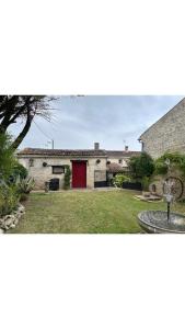 una casa con una puerta roja y un patio en Maison Le puits du bonheur, en La Celle-sous-Gouzon