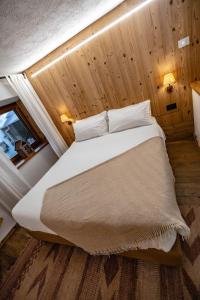 ein großes Bett in einem Zimmer mit Holzwänden in der Unterkunft Lo Péyo - Le Four des Alpes in Rhemes-Saint-Georges