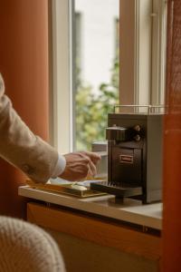 a person pointing at a coffee maker on a counter at Four Suites Copenhagen in Copenhagen