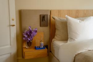 a nightstand with a bottle of beer and a flower on a bed at Four Suites Copenhagen in Copenhagen