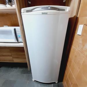 einen weißen Kühlschrank in einer Küche neben einer Mikrowelle in der Unterkunft bairro Vila bandeirantes - apto 3 quartos com ar condicionado em condomínio in Campo Grande