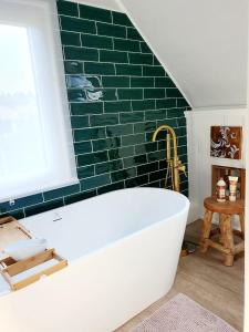 een badkuip in een badkamer met een groene bakstenen muur bij Geschmackvolle Wohnung 65qm in Solingen NRW in Solingen