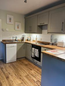 a kitchen with gray cabinets and white appliances at Charming cottage close to the Cairngorms in Ballindalloch