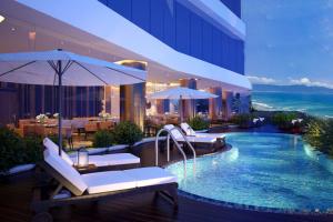 a hotel with a swimming pool with chairs and umbrellas at Avatar Danang Hotel in Da Nang