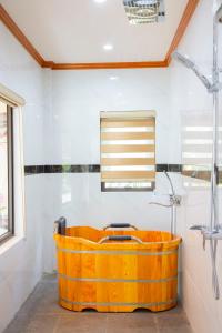Una bañera naranja en un baño con ventana. en Tam Coc Kamili Bungalow & Homestay, en Ninh Binh