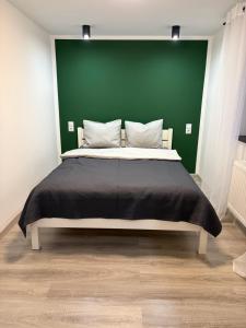 a bedroom with a large bed with a green wall at Piękna Góra House in Gołdap