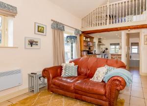 a brown leather couch in a living room at Wilf's Barn, romantic cottage with free parking in Wedmore