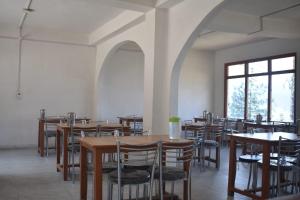 a dining room with tables and chairs and windows at Hotel SSS The Chanshal Retreat in Khashdhār