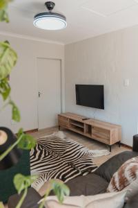 a living room with a television and a zebra rug at Welverdiend - Unit 1 in Bloemfontein