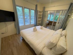 a bedroom with a white bed with pillows and a television at Zen Beach Oasis - Balinese Beachfront House with Stunning Sea View in Koh Phangan