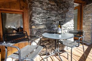 a table and chairs on a patio with a stone wall at Petit Câlin - Le Four des Alpes in Rhemes-Saint-Georges