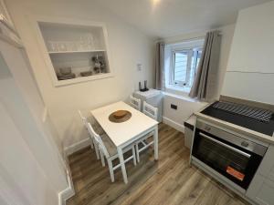 a small kitchen with a white table and a stove at Cinema room apartment 2 in Basildon +7 photos