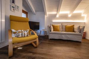 ein Wohnzimmer mit einem gelben Stuhl und einer Couch in der Unterkunft Petit Câlin - Le Four des Alpes in Rhemes-Saint-Georges