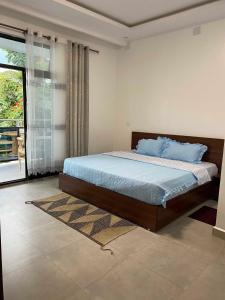 a bedroom with a bed and a large window at maman home apartment in Gisenyi