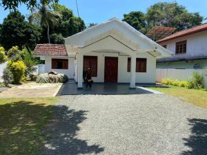 a small white house with a red door at Hiri Relax Hostal in Dickwella