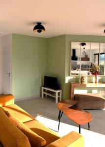 een woonkamer met 2 banken en een televisie bij L'échappée Bourguignonne in La Roche-Vineuse