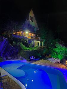 a swimming pool in front of a house at night at Pousada Chale da Montanha in Petrópolis