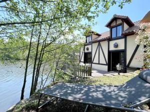 a house next to the water with a chair in front at Chalet au bord d'un lac privé in Saint-Estèphe