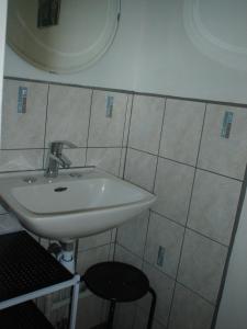 La salle de bains est pourvue d'un lavabo blanc et d'un tabouret. dans l'établissement Gite "Etape à Coucy", à Coucy-le-Château-Auffrique