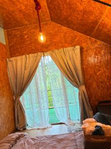 een slaapkamer met een raam met gordijnen en een bed bij มาค่ะ ฟาร์มสเตย์ ห้วยเขย่ง สวนคุณตา สวนทุเรียนทองผาภูมิ in Ban Diso