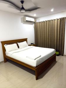 Un dormitorio con una cama grande con sábanas blancas. en Sathya Inn Guruvayur, en Trichūr