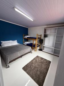 ein Schlafzimmer mit einem Bett und einer blauen Wand in der Unterkunft Casa Quintal de Bertioga Centro in Bertioga