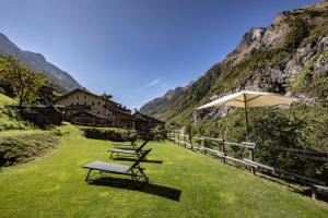 a group of picnic tables with an umbrella in the grass at Lo Micho - Le Four des Alpes in Rhemes-Saint-Georges
