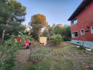 ein Hof neben einem roten Haus mit Bäumen in der Unterkunft El Jardin de Sauce in Monte Hermoso