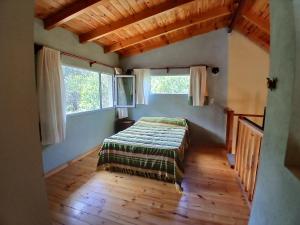 ein Schlafzimmer mit einem Bett in einem Zimmer mit Fenstern in der Unterkunft El Jardin de Sauce in Monte Hermoso