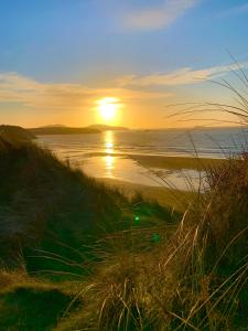 una puesta de sol sobre una playa con el océano y la hierba en Craig-Y-Mor Suites With Sea Views Whitesands Bay St Davids, en St. Davids 67 fotos más
