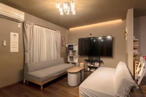 a hospital room with a couch and a tv at Noctis豊田 ジャグジー肩湯付お風呂75型TV 最大12名宿泊可能 in Toyota