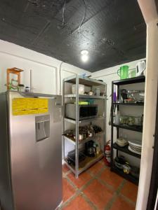 a kitchen with a stainless steel refrigerator and shelves at Cabin -Treehouse La Tigra in San Gerardo