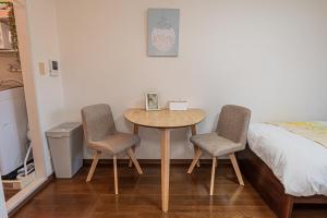 una habitación con una mesa y dos sillas y una cama en sakura 303, en Tokio