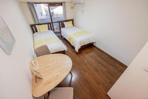Una pequeña habitación con dos camas y una mesa. en sakura 303, en Tokio