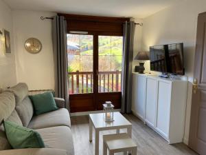 a living room with a couch and a sliding glass door at Chalets des Evettes- appartement vue montagne in Flumet